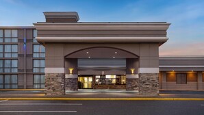 A hotel entrance with a stone facade, large windows, and an arched overhang. - Days Hotel by Wyndham Toms River Jersey Shore (Toms River)