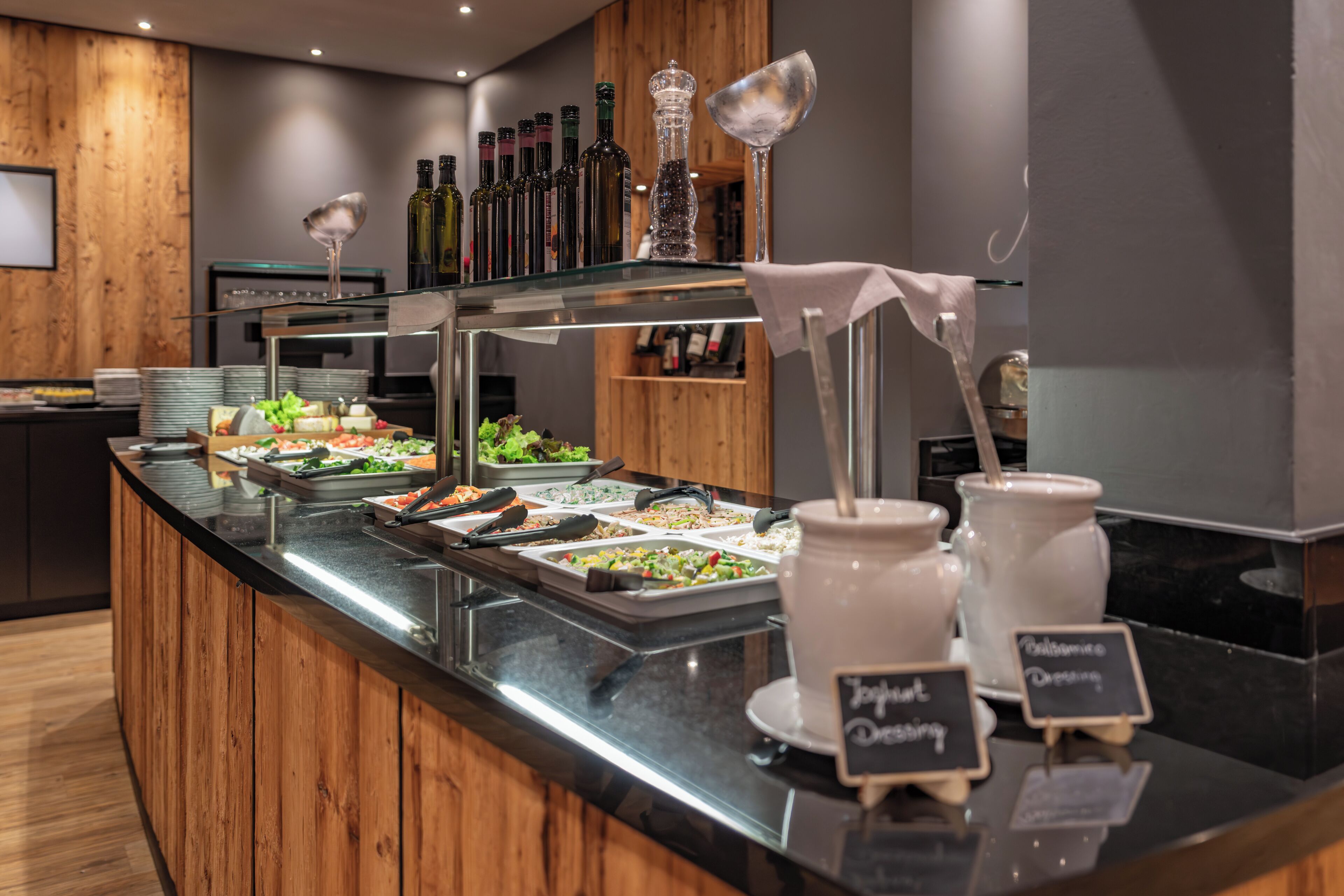 Un mostrador de buffet con diversas opciones de comida, una selección de botellas de vino y una estación de café.