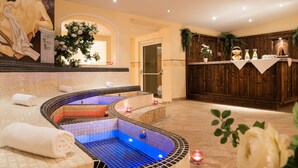A spa area with two hot tubs, a reception desk, and a mural on the wall. - Hotel Gasthof Brücke (Mayrhofen)