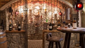 A stone-walled bar area with wooden furniture and bottles of wine. - Hotel Gasthof Brücke (Mayrhofen)