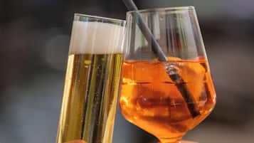 Two people holding glasses of beer and a cocktail.