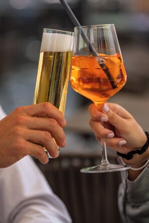 Two people holding glasses of beer and a cocktail.