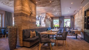 A modern interior with a wooden accent wall, a large vase, a sofa, chairs, and a dining area. - Hotel Gasthof Brücke (Mayrhofen)