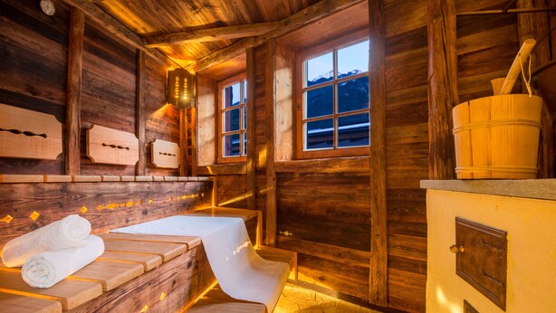 A wooden cabin interior with a sauna, wooden benches, and a wooden stove. - Hotel Gasthof Brücke (Mayrhofen)
