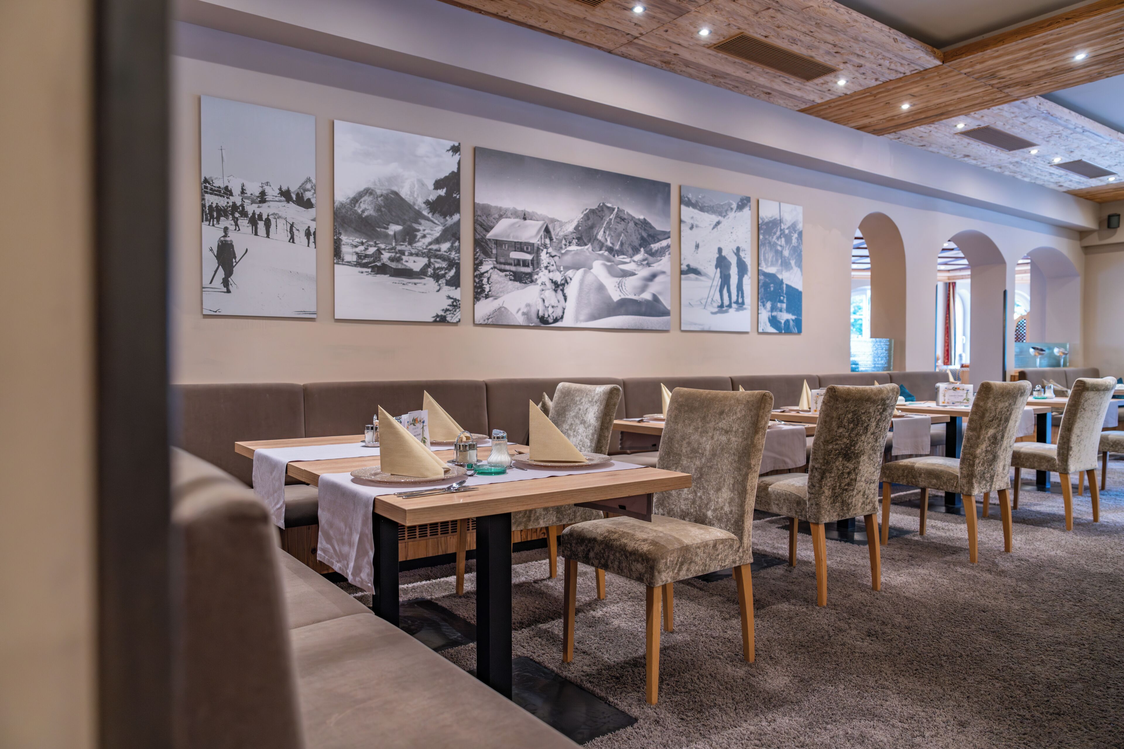 A restaurant with a long table set for dining, cushioned seating, and a wall with black and white photographs.