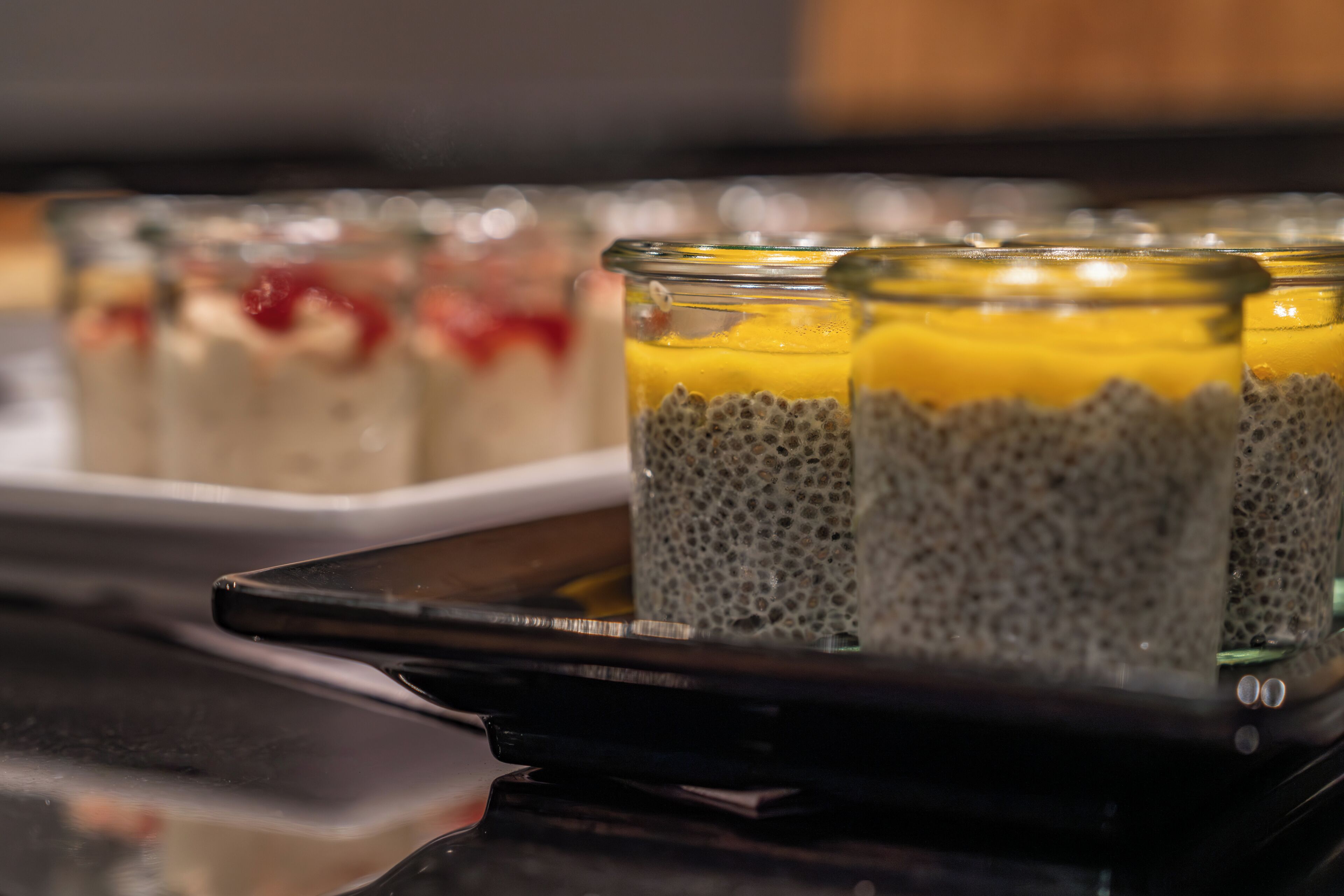 A tray with several glass containers of chia pudding topped with fruit.