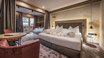 A hotel room with a large bed, a round table, a chair, and a view of the outside.