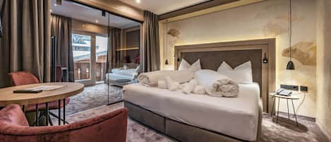 A hotel room with a large bed, a round table, a chair, and a view of the outside.