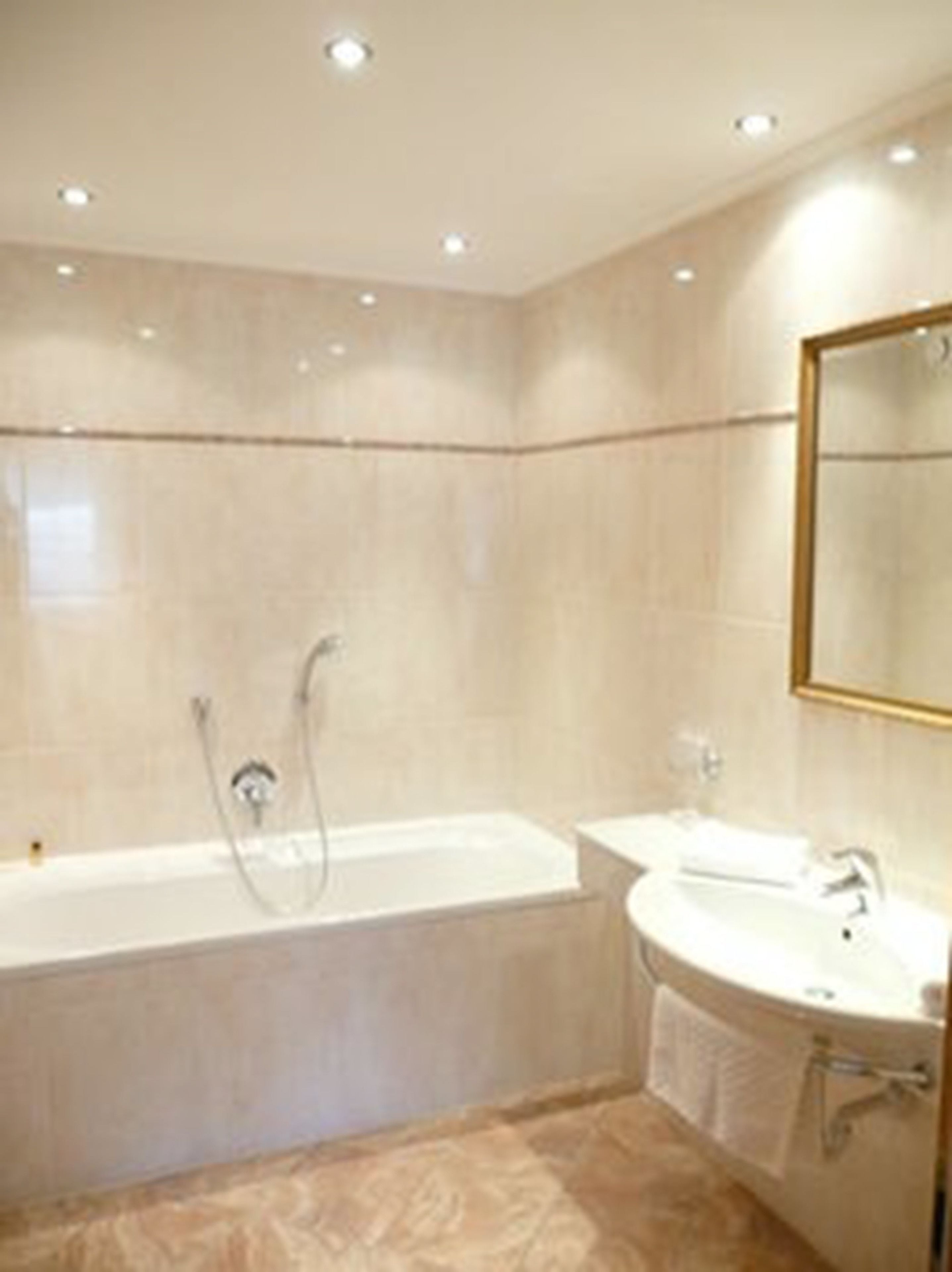 Une salle de bain moderne avec une baignoire, un lavabo et un miroir.