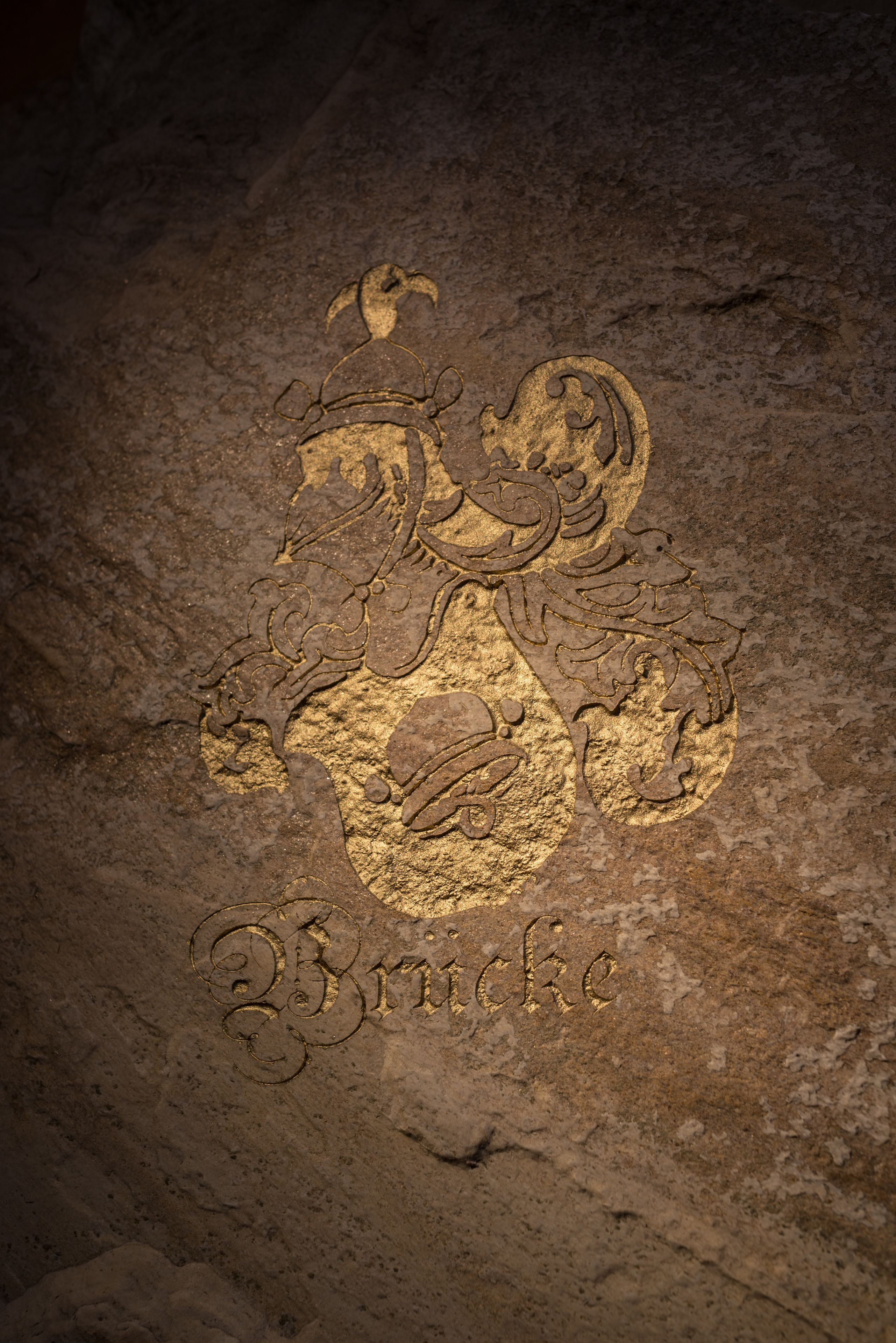Un emblema dorado grabado en una superficie de piedra con la palabra 