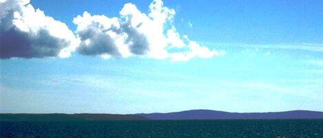 A view of the ocean with a distant landmass under a clear sky.