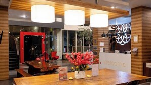 A modern dining area with a wooden table, black chairs, and three pendant lights. - Kalya Hotel Bandung (Bandung)