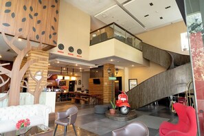A modern lobby with a staircase, seating areas, and a red scooter. - Kalya Hotel Bandung (Bandung)