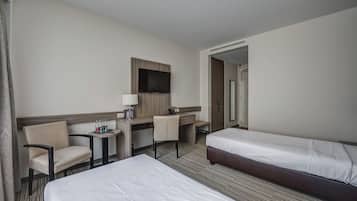 A hotel room with two beds, a desk, a chair, a TV, and a mirror.