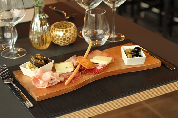 A wooden board with various cheeses, cured meats, and olives.