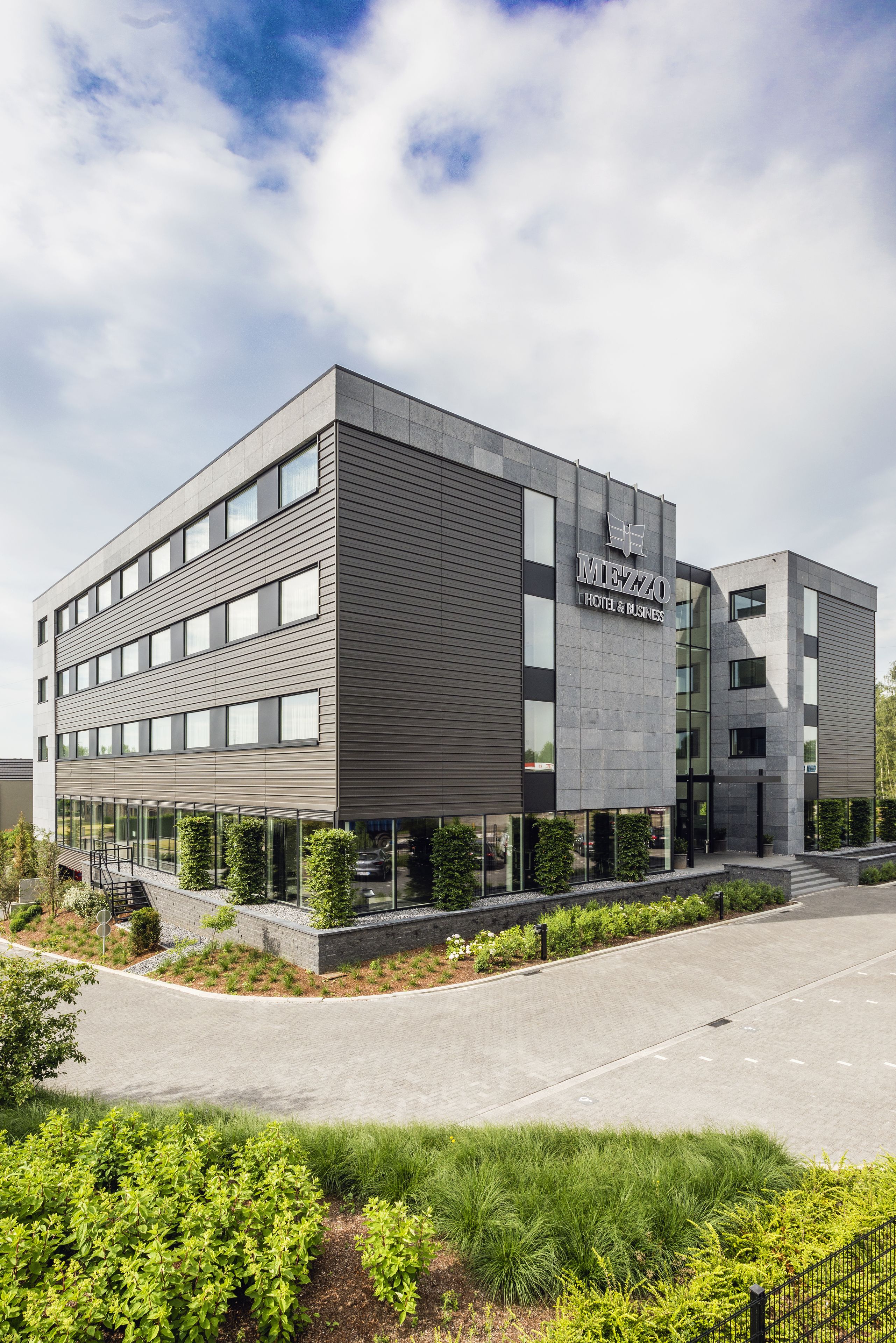 A modern hotel building with a flat roof, large windows, and a sign reading "MIEZZO HOTEL & BUSINESS".