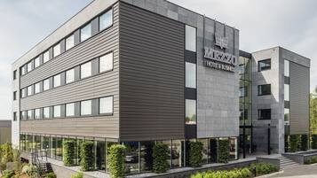 A modern hotel building with a flat roof, large windows, and a sign reading "MIEZZO HOTEL & BUSINESS".