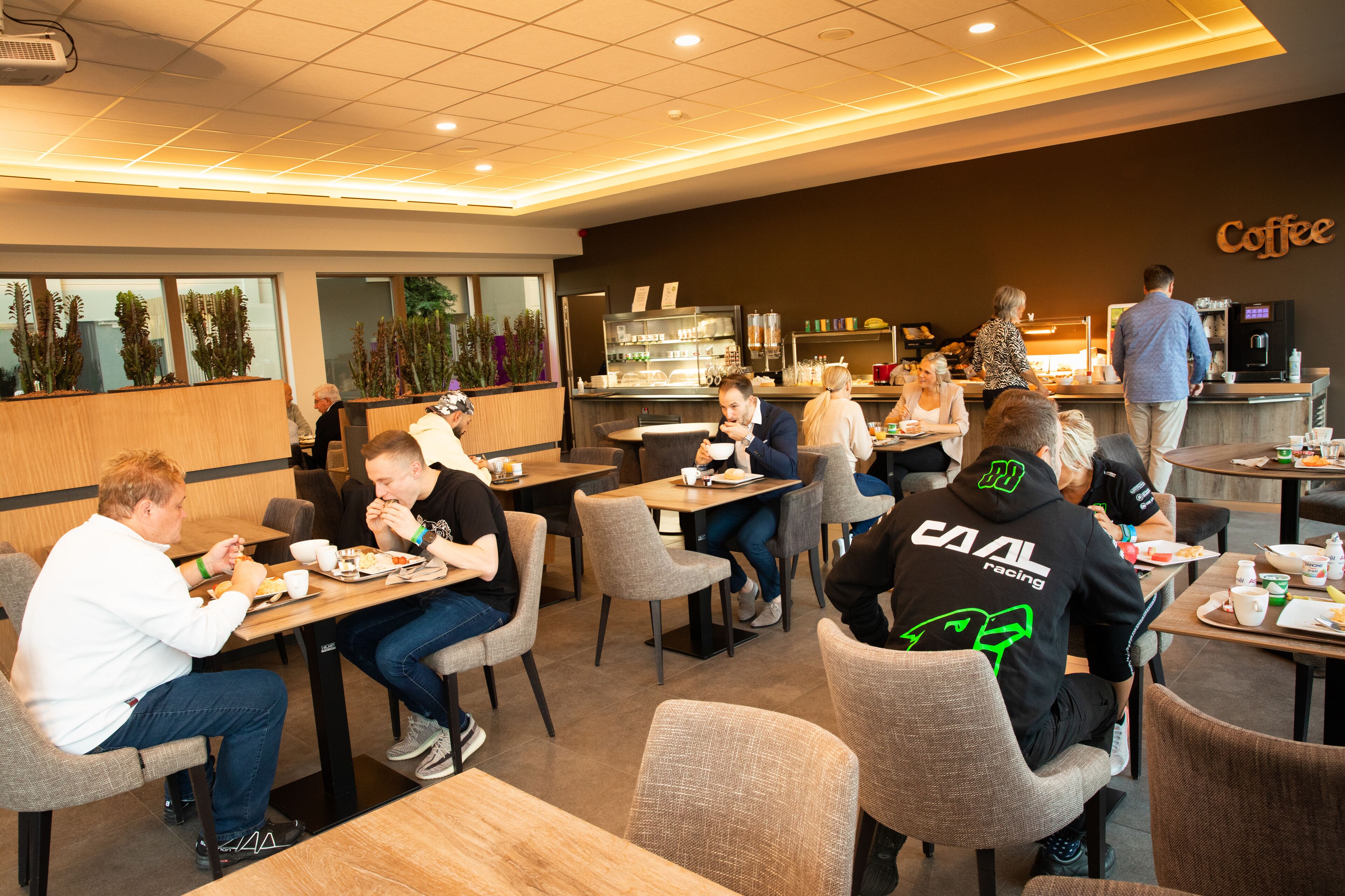Una cafetería con varias mesas y sillas, una barra de café y un mostrador con una máquina de café.