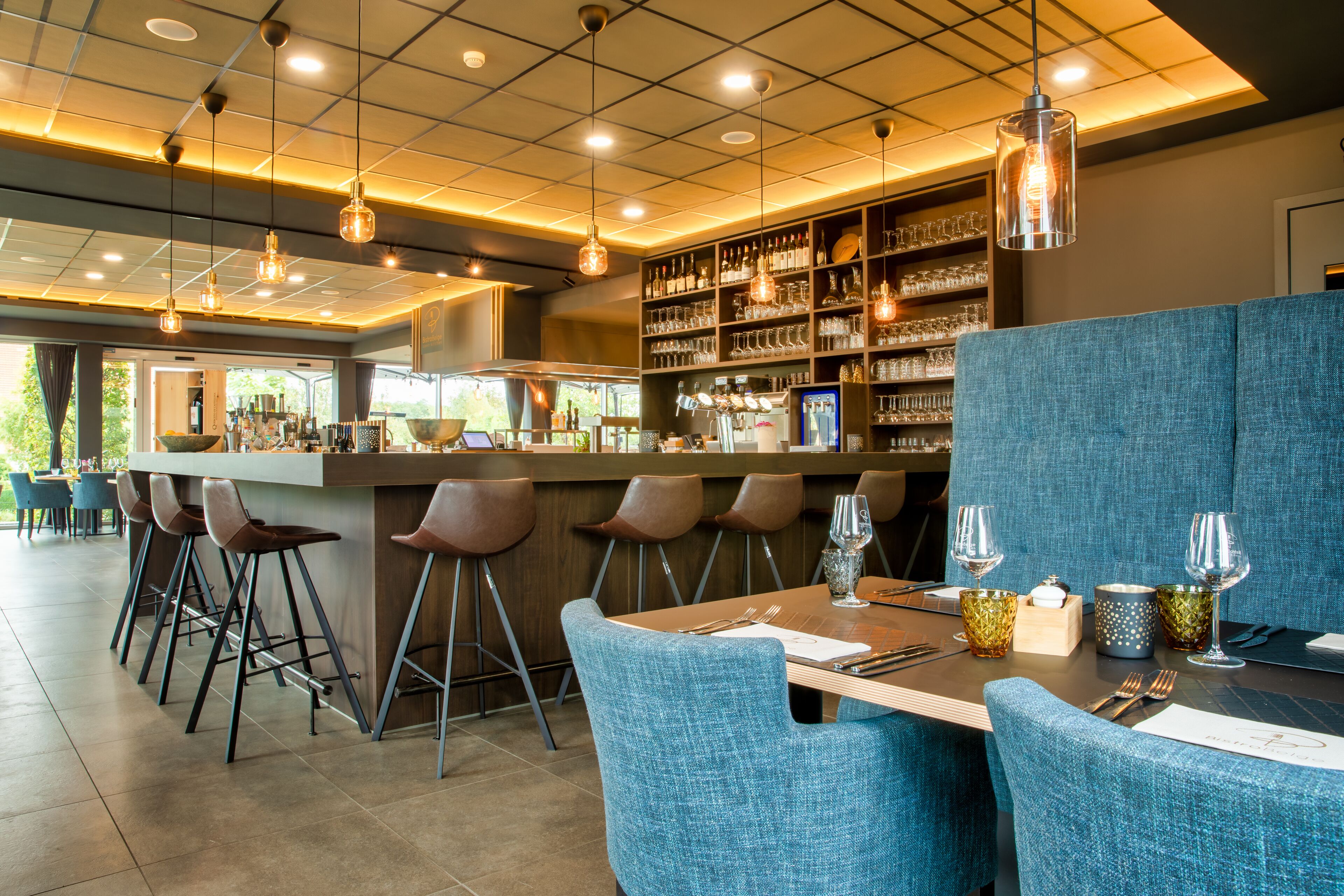 Un interior de restaurante con barra, sillas altas y una zona de estar con mesas y sillas.