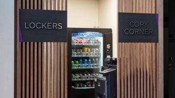 Een hotelingang met een automaat en een bordje voor 'Lockers' en 'Copy Corner'.