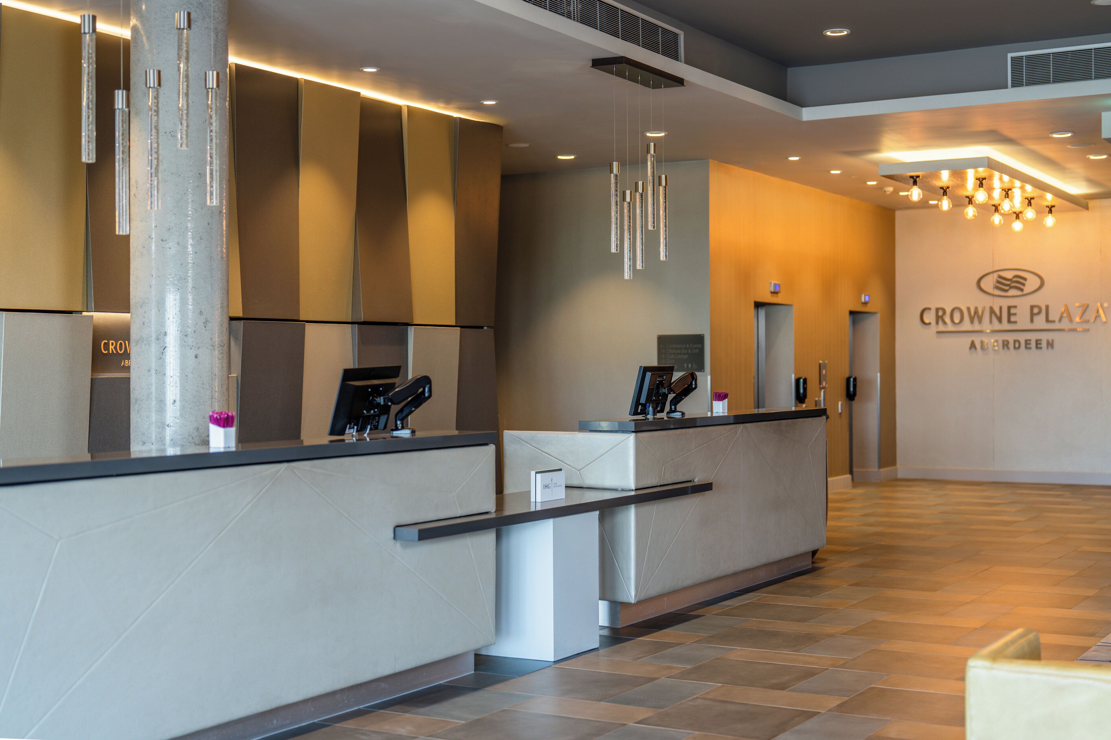 Ett modernt receptionsområde med en receptionsdisk, en stor pelare och en skylt för Crowne Plaza.