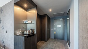 A modern hotel hallway with a built-in kitchenette, a carpeted floor, and a door leading to a room. - Crowne Plaza Aberdeen Airport by IHG (Aberdeen)