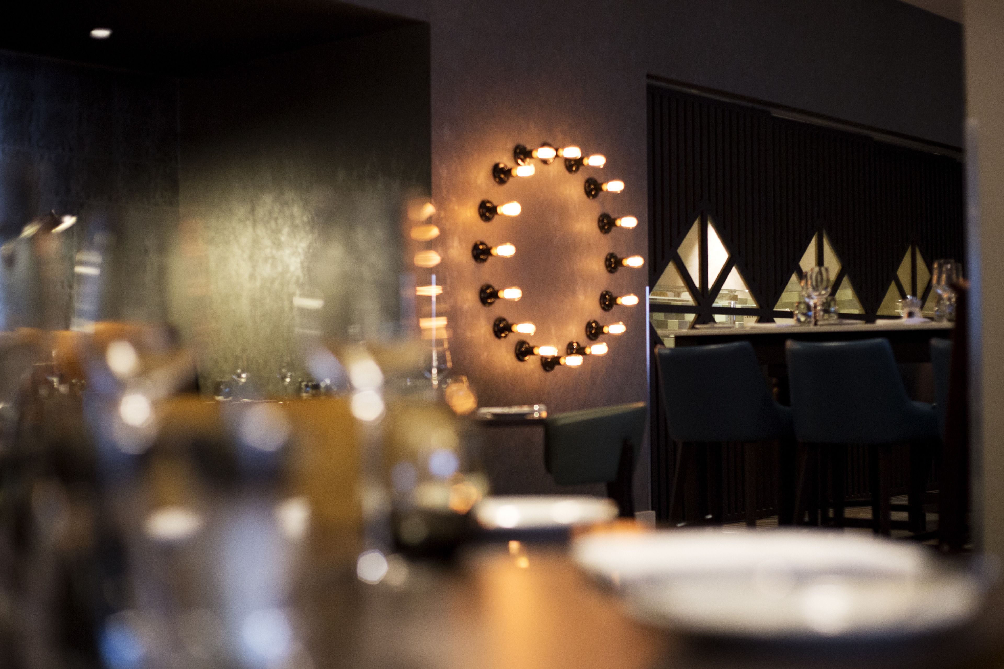 A restaurant interior with a bar area, tables, and chairs.