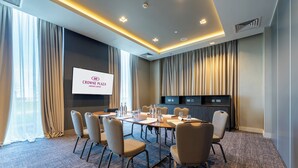 A conference room with a large screen displaying "CROWNE PLAZA," beige chairs, a long table, and a carpeted floor. - Crowne Plaza Aberdeen Airport by IHG (Aberdeen)