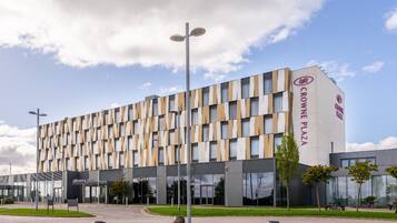 A modern hotel with a distinctive facade, a central entrance, and a circular plaza with seating.