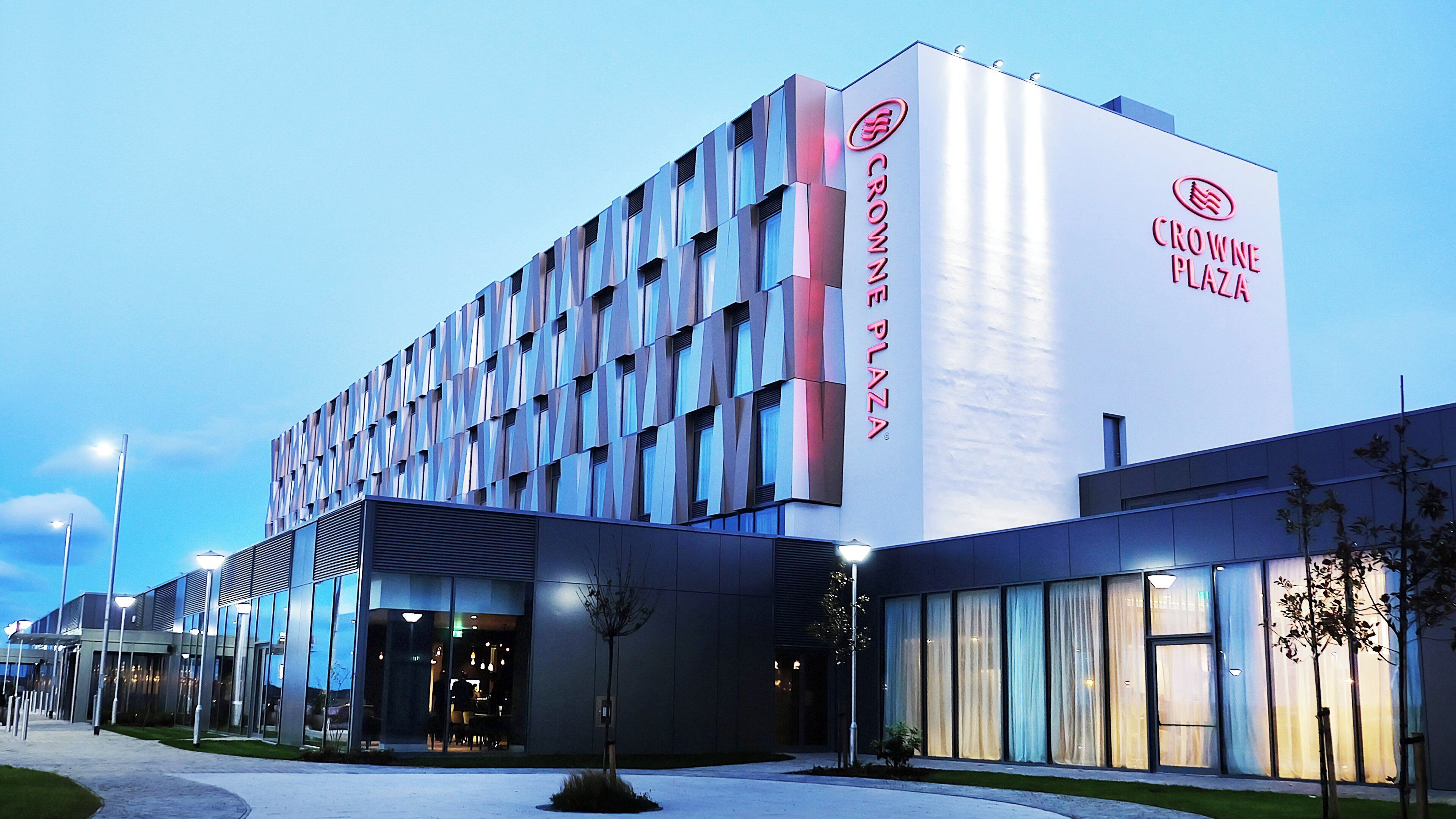 A modern hotel building with a prominent sign for 'Crown Plaza'.