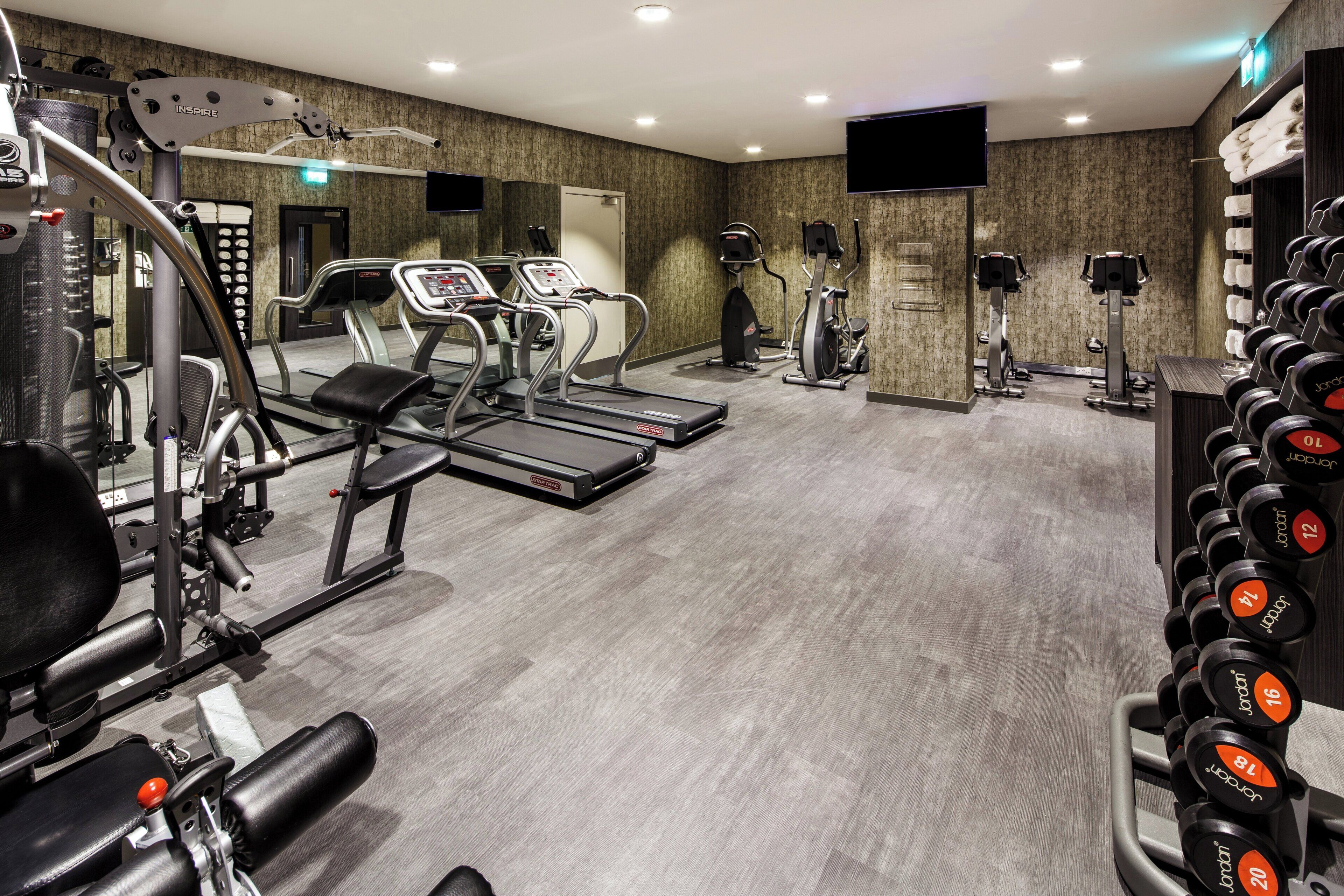 Un gimnasio con cintas de correr, elípticas y pesas sueltas.