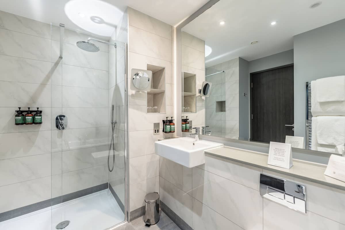 Une salle de bain moderne avec une douche à parois de verre, un lavabo blanc et un grand miroir.