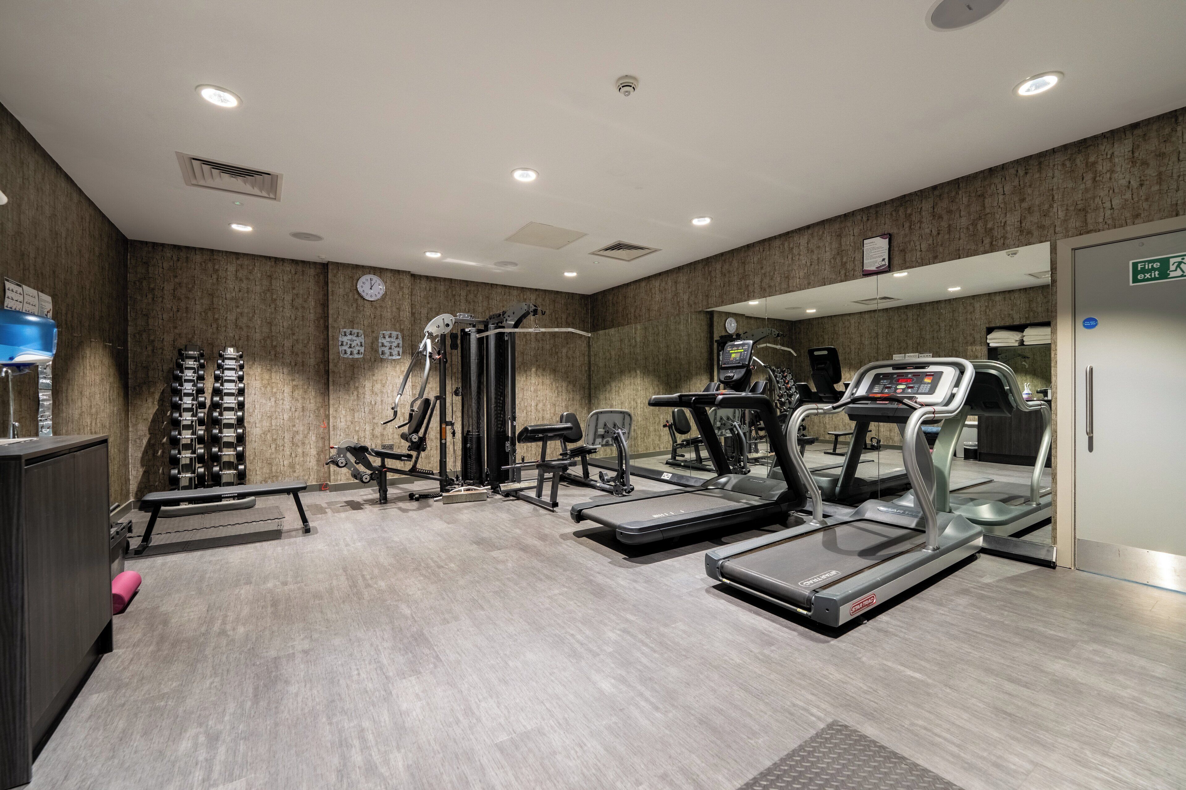 A modern gym with treadmills, ellipticals, and free weights.
