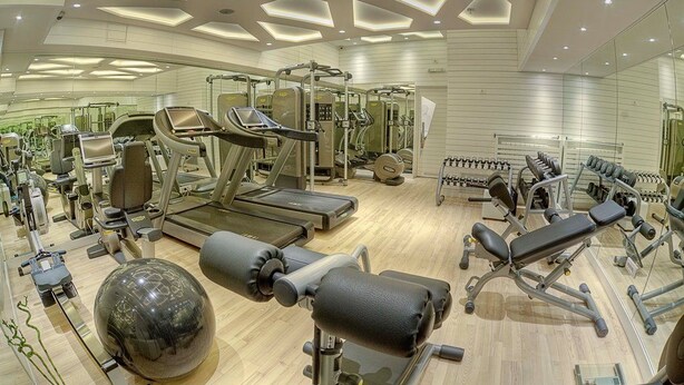 A modern gym with various exercise equipment, including treadmills, weight machines, and a large exercise ball. - Moskva (Belgrade)
