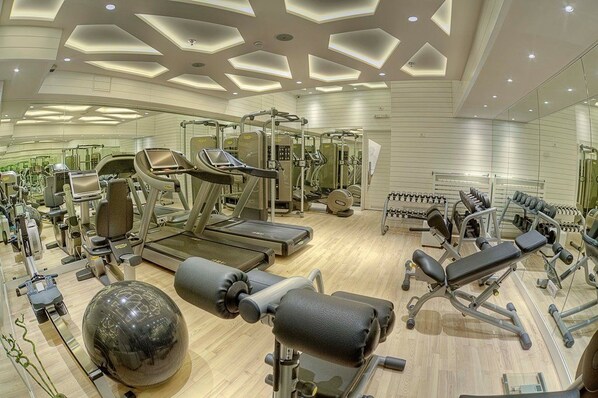 Un gimnasio moderno con diversos equipos de ejercicio, incluyendo cintas de correr, máquinas de pesas y una pelota grande para ejercicio.