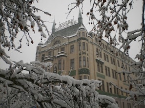 A historic building with a prominent tower and snow-covered branches in the foreground.