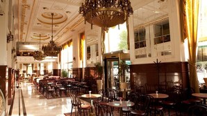 A spacious hotel lobby with multiple seating areas, a grand chandelier, and large windows allowing natural light. - Moskva (Belgrade)