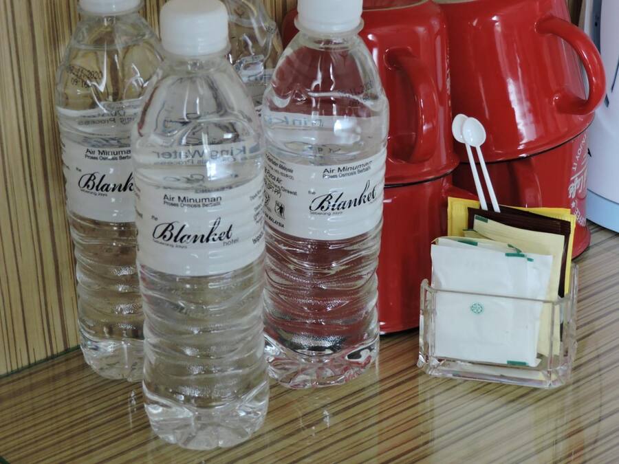 Three bottles of water labeled 'Blanket hotel' and a red mug with a spoon.