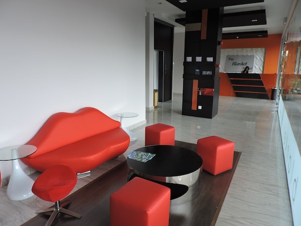 A modern lobby with red seating, a glass table, and a black round table.