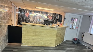 A hotel reception area with a wooden reception desk, a black marble wall, and an American flag. - Huntington Inn (Huntington)