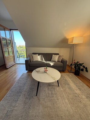A modern living room with a grey sofa, a round coffee table, a floor lamp, and a view of a balcony. - Green Park Apartments (Dubrovnik)