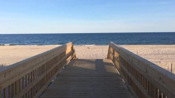 A wooden boardwalk leading to a sandy beach with the ocean in the background. - Clegg's Hotel (Ocean Beach)
