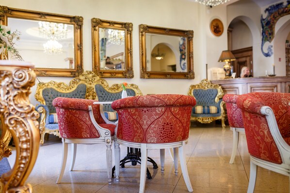 A room with ornate furniture, including red upholstered chairs and a white table, with large mirrors on the walls. - Boutique Spa Hotel Aqua Marina (Karlovy Vary)