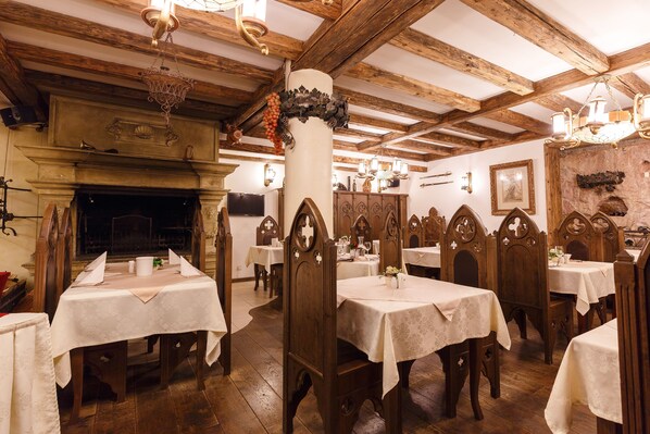 A traditional inn with wooden beams and a fireplace. Tables are set with white tablecloths and candles. - Boutique Spa Hotel Aqua Marina (Karlovy Vary)