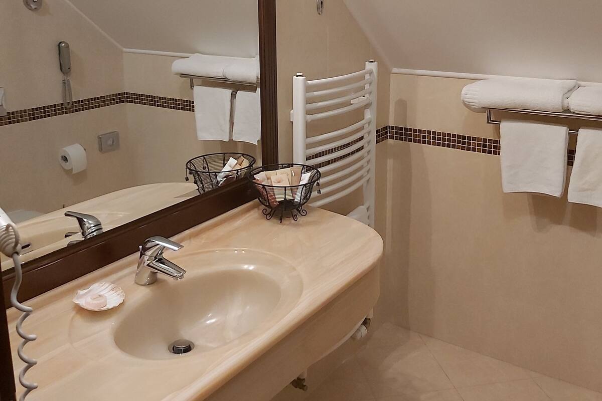 A bathroom with a sink, mirror, towel rack, and shower.