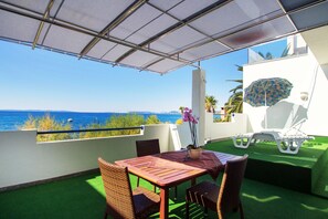 A balcony with a view of the sea, a table with chairs, and a white umbrella. - Beachfront Villa Mediteran (Podstrana)