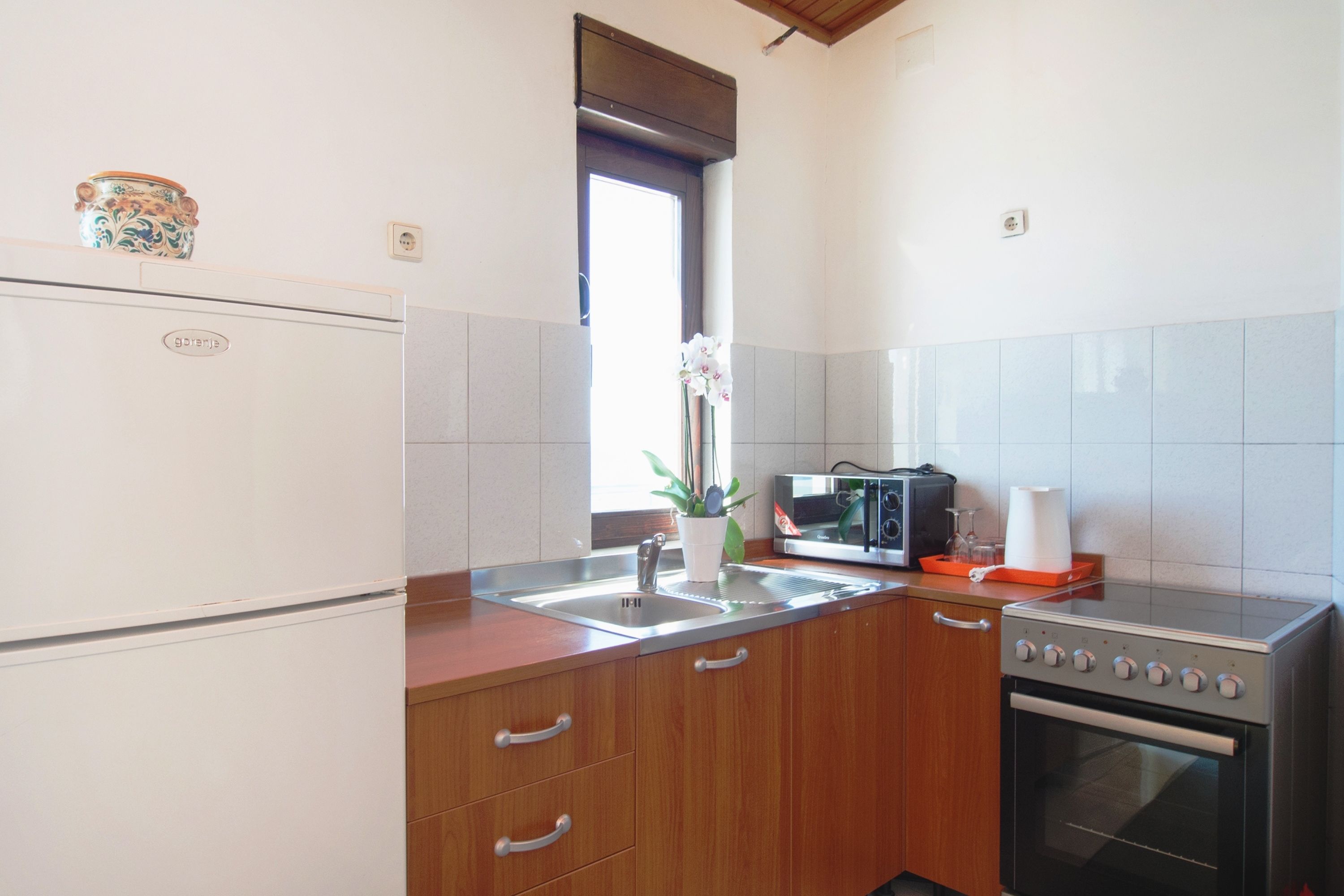 A compact kitchen with a refrigerator, microwave, stove, and sink.