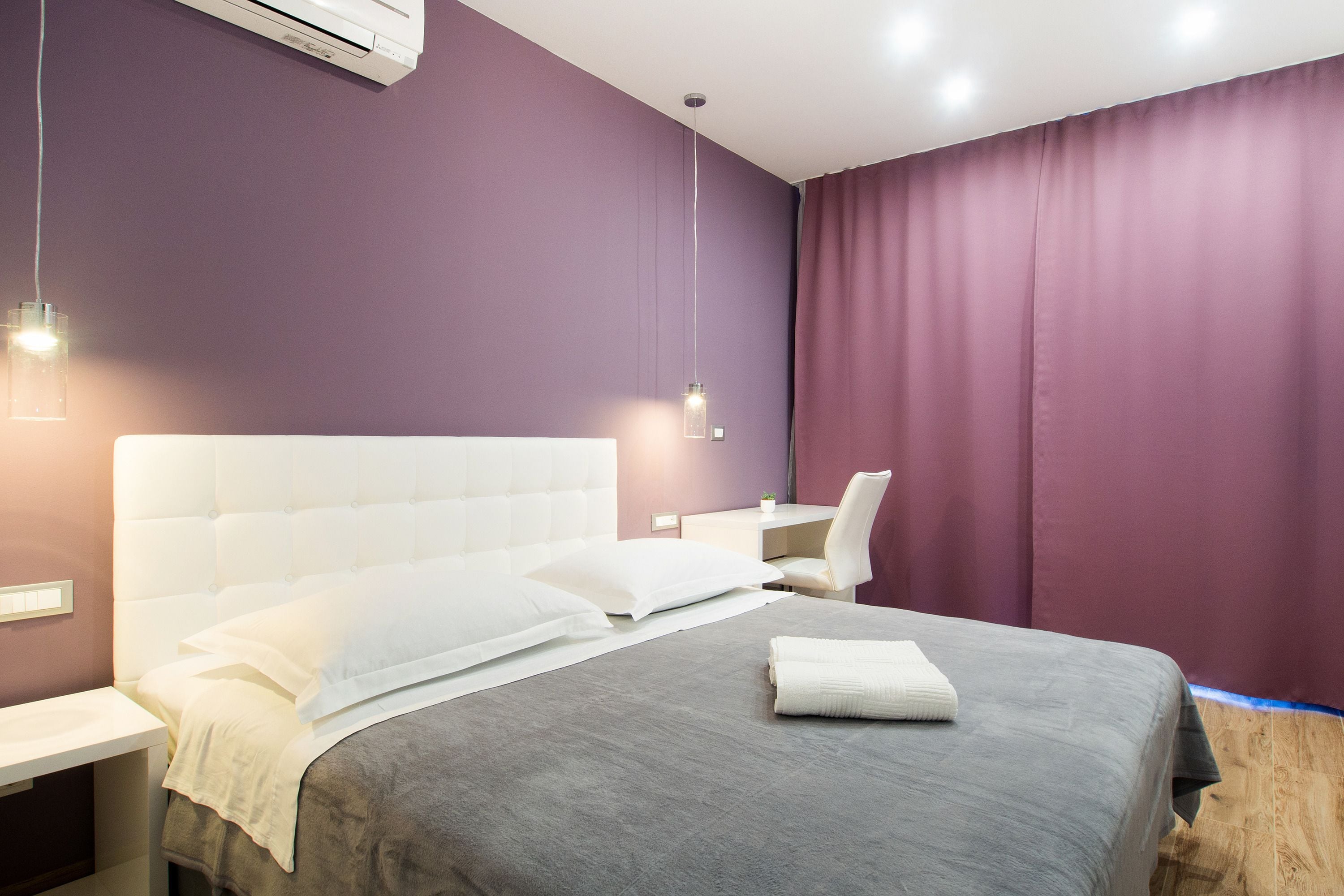 A modern hotel room with a large bed, a desk, and a chair.