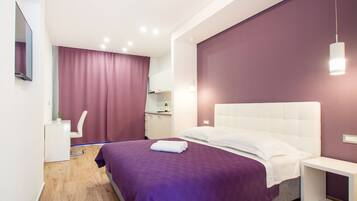 A modern bedroom with a large bed, a bedside table, a desk, and a chair.