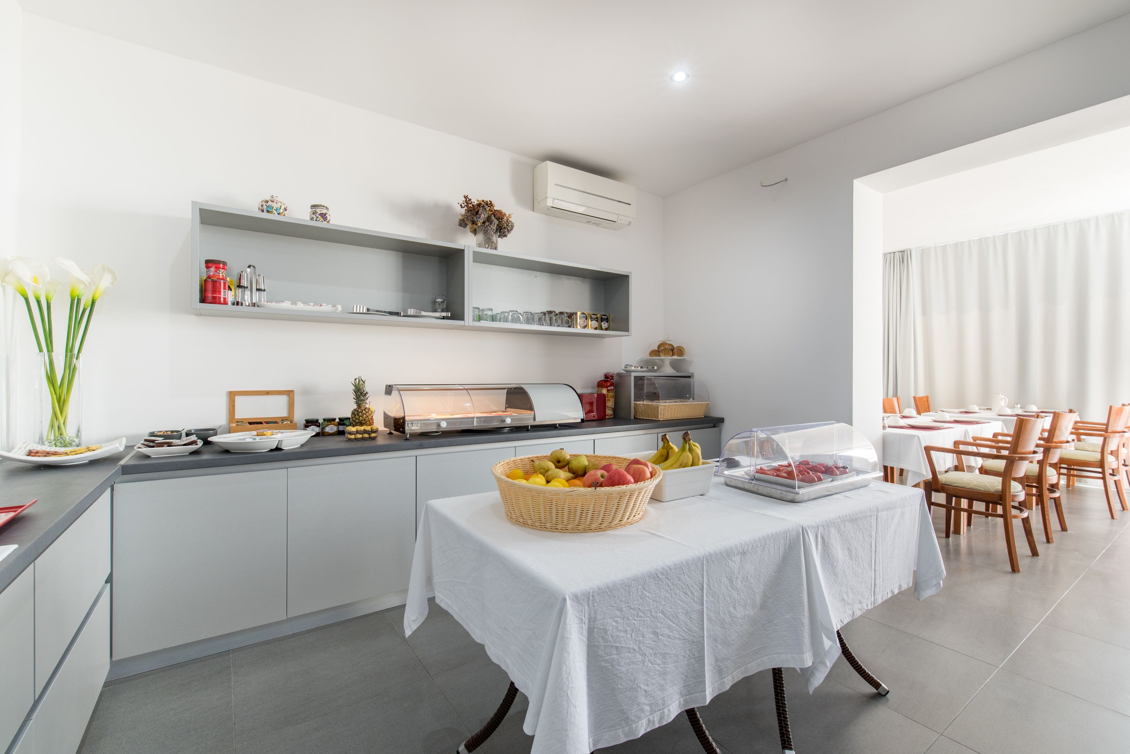 Une cuisine moderne avec un buffet, des meubles blancs et un coin repas comprenant des chaises et des tables.